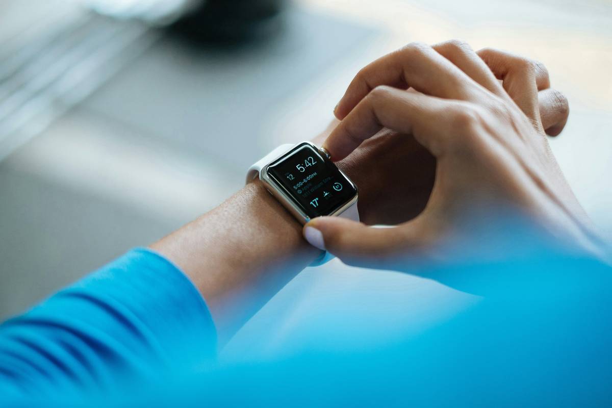 Siri smart clock tips: User adjusting settings on bedside smart clock with iPhone nearby